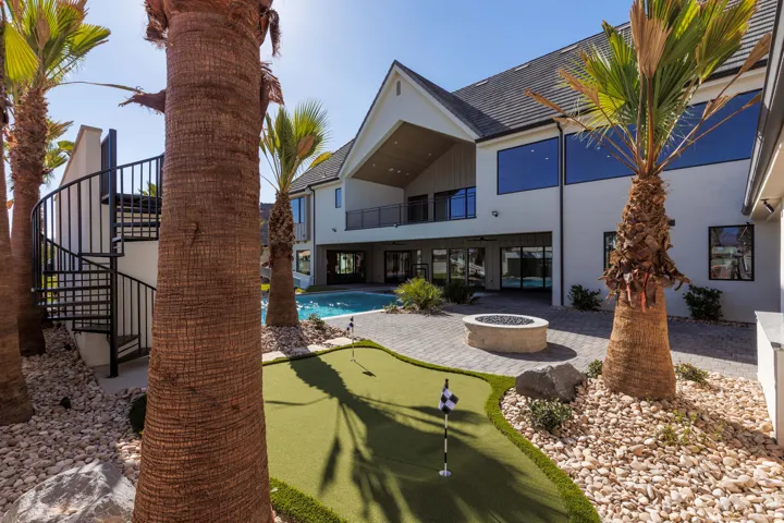 Spacious backyard with a putting green, built-in fire pit, swimming pool, and a spiral staircase leading to an upper balcony