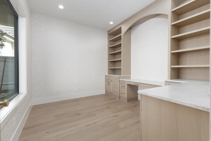 Built-in blonde wood cabinetry with integrated desks and open shelving