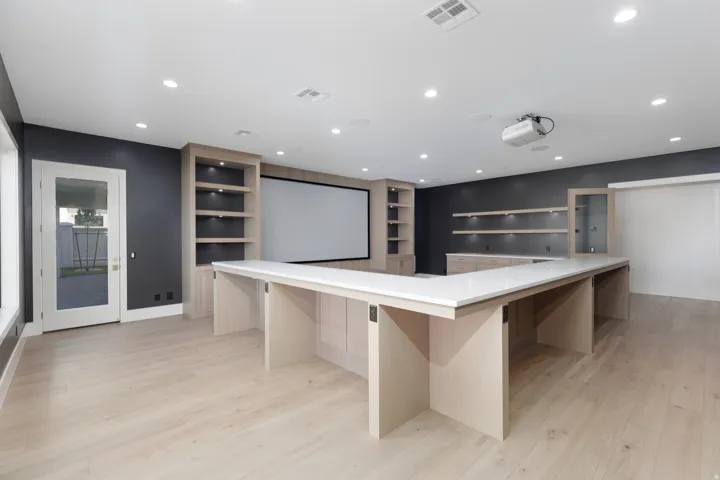 Wood-finish flooring, recessed lighting, integrated projector, built-in shelving, and a large projection screen