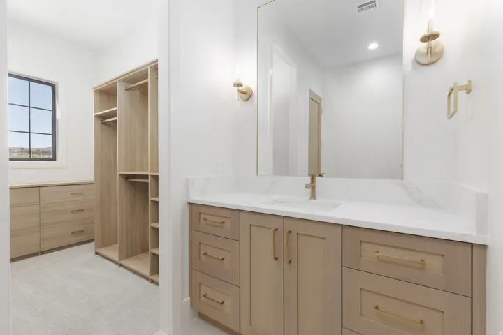Integrated vanity with a single basin sink, light-toned cabinetry, and a large mirror