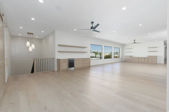 Spacious room featuring light wood-finish flooring, recessed lighting, and multiple windows