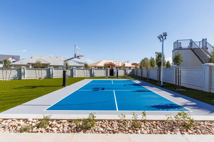 Outdoor sports court with painted blue surface and integrated basketball hoop