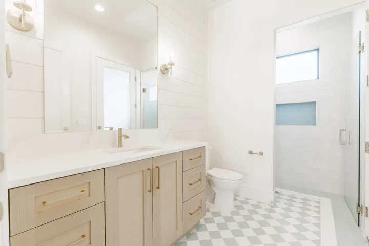 Light wood-finish vanity with gold-tone hardware, rectangular undermount sink, and white countertop