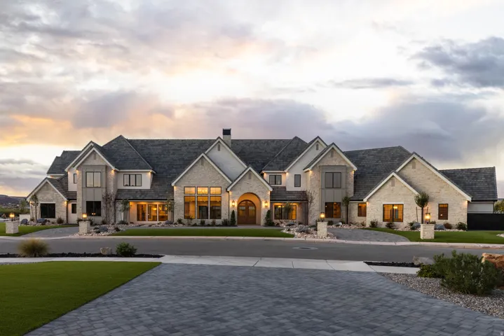 Stone and stucco exterior with multiple gables, large multi-pane windows, and a paved driveway