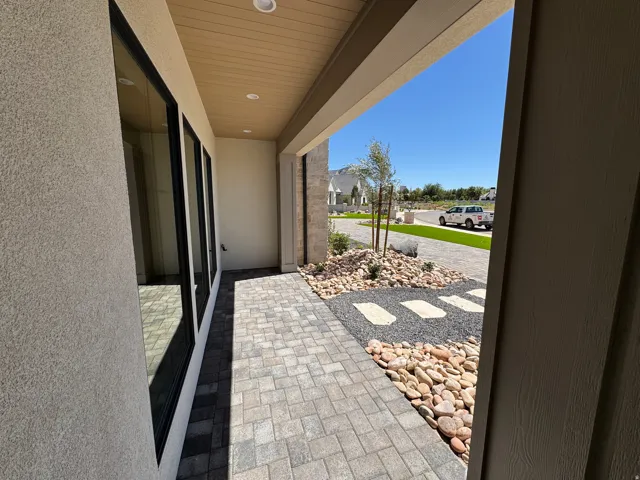 Covered entry with recessed lighting, paver walkway, and decorative rock landscaping