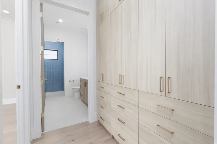Built-in wardrobe system with light wood-finish cabinetry and gold-tone hardware
