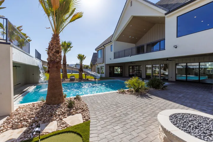 Expansive backyard featuring a swimming pool, integrated water feature, paver patio, and built-in fire pit