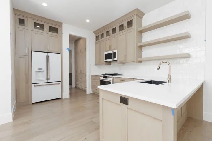 Recessed lighting, wood-finish flooring, custom cabinetry with glass-front uppers, white subway tile backsplash, and a white countertop with an undermount sink