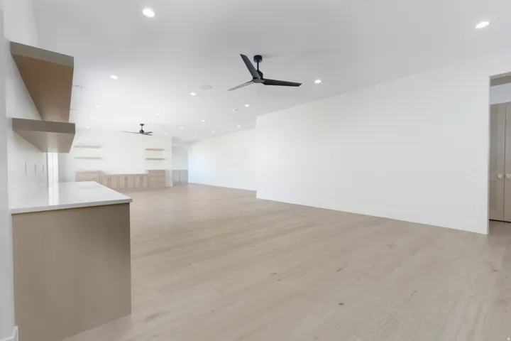 Expansive room featuring light wood-finish flooring, recessed lighting, and modern ceiling fans