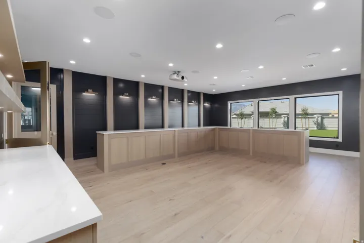Recessed lighting, wood-finish flooring, built-in cabinetry with white countertops, wall sconces, and multiple windows