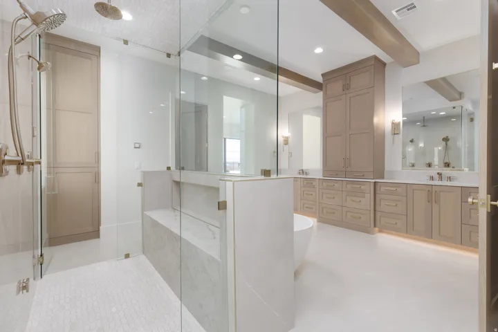 Glass-enclosed shower with a built-in bench, hexagon tile flooring, and dual shower heads