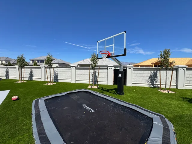 Expansive green space featuring artificial turf, a permanent basketball hoop, and a perimeter wall with architectural detailing