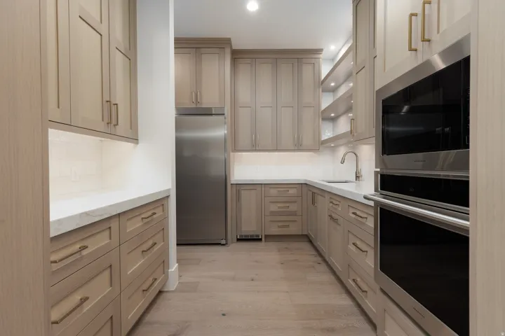 Light wood-finish cabinetry, stainless steel appliances, light-toned countertops, wood-finish flooring, and integrated display shelving