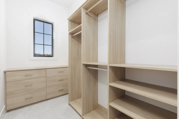 Custom closet system with adjustable shelving, integrated drawers, and a grid-paned window
