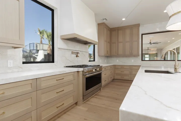 Full kitchen featuring light wood-finish cabinetry, white countertops, built-in stainless steel range, and light wood-finish flooring