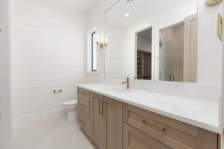 Light wood-finish vanity with ample storage, white countertop, and single basin