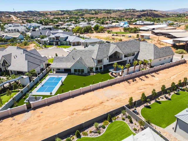 Expansive property featuring a multi-level architectural design with a gabled roofline, a private sports court, and a meticulously maintained artificial turf lawn