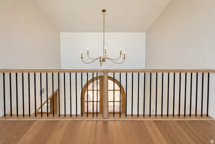 Wood-finish flooring with a railing featuring a wood-finish handrail and black balusters