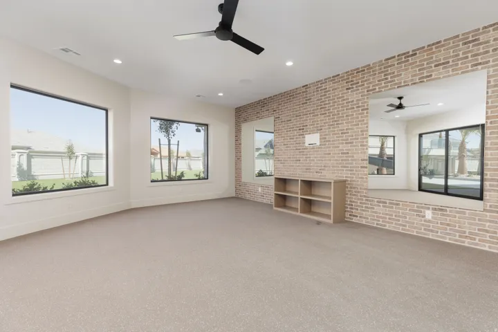 Recessed lighting, ceiling fan, carpet flooring, brick accent wall, and built-in shelving