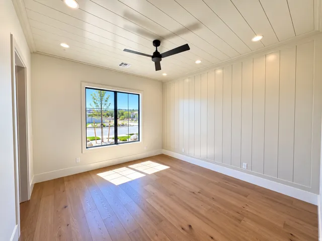 Wood-finish flooring with a ceiling fan, recessed lighting, and a paneled accent wall