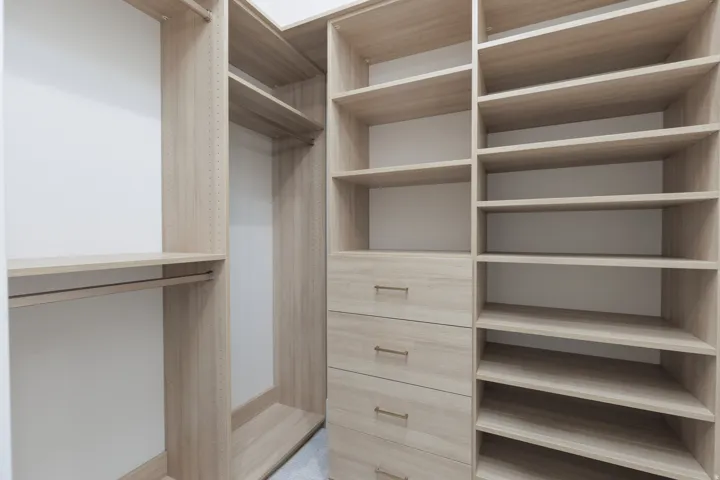 Custom closet system featuring wood-finish shelving, built-in drawers with modern hardware, and dedicated hanging rods