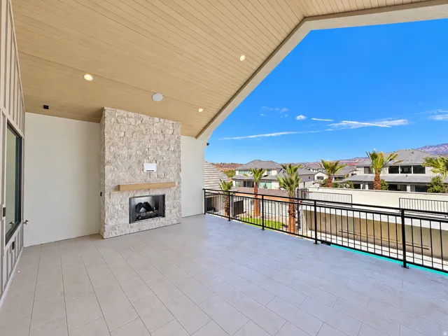 Expansive covered patio featuring a stone-clad fireplace with wood mantel, recessed lighting, wood-finish ceiling, and durable tile flooring