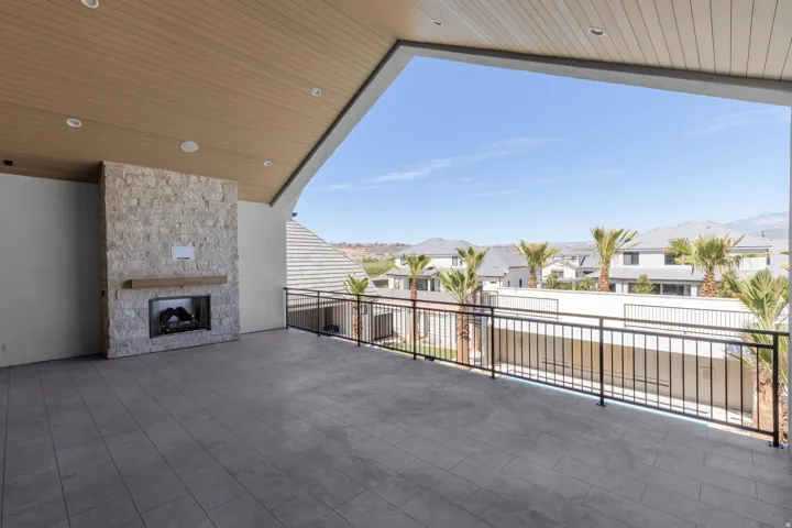 Spacious outdoor patio with wood-finish ceiling, recessed lighting, tile flooring, and a stone fireplace with a wood mantle