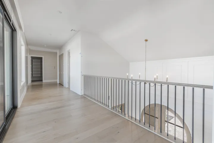 Wide plank wood-finish flooring, sliding glass door, built-in shelving, vaulted ceiling, and wrought iron railing