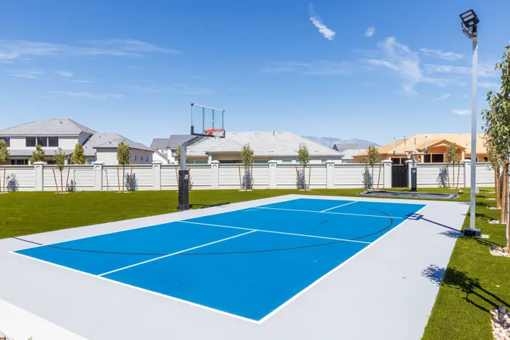 Outdoor multi-sport court featuring a basketball hoop and integrated lighting