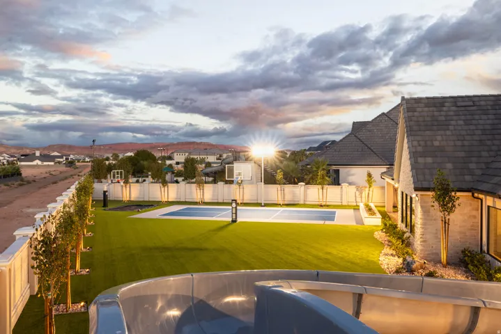 Expansive backyard featuring a manicured lawn, multi-sport court, and perimeter privacy fencing