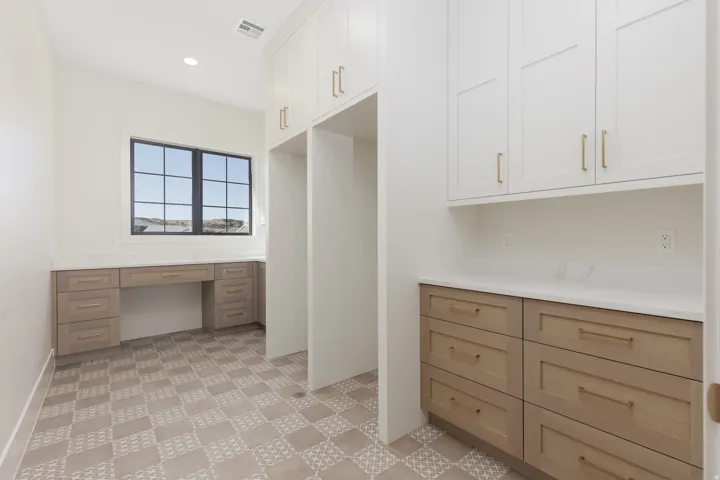 Built-in desk area with light wood-finish cabinetry, white countertop, and a multi-pane window
