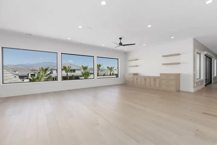Expansive room featuring light wood-finish flooring, recessed lighting, and a ceiling fan