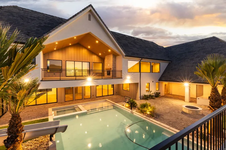 Exterior featuring a contemporary design with a balcony, a swimming pool with an integrated spa, a fire pit, and extensive paved patio areas