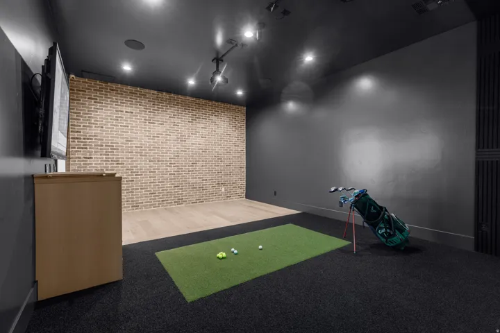 Exposed brick accent wall, recessed lighting, ceiling-mounted projector, dark wall finishes, and a combination of wood-finish and dark carpet flooring