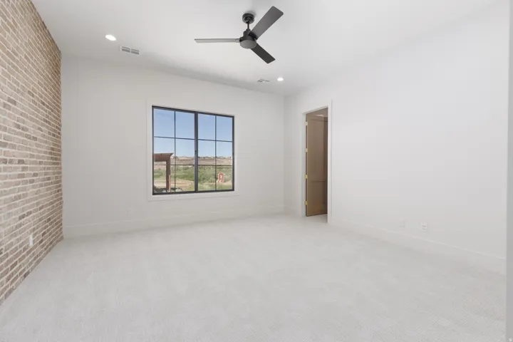 Exposed brick accent wall, black grid window, recessed lighting, and a ceiling fan