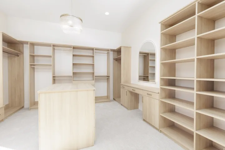 Expansive closet featuring extensive built-in shelving, hanging rods, central island, integrated vanity, and a decorative chandelier