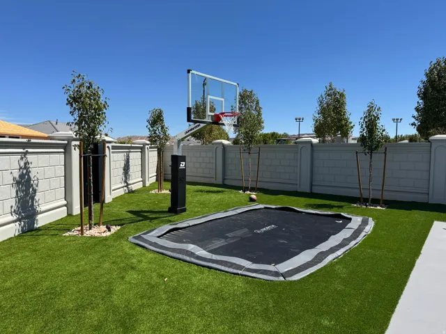 Manicured synthetic turf lawn, solid masonry privacy walls, and young trees