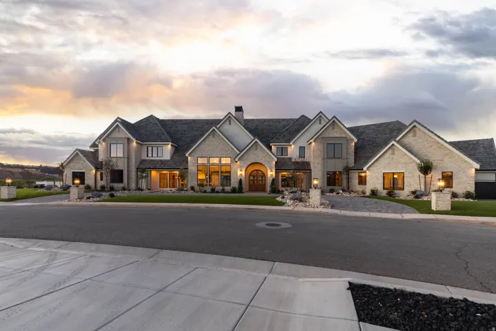 Stately stone exterior with multiple gabled rooflines, arched entry, and large picture windows