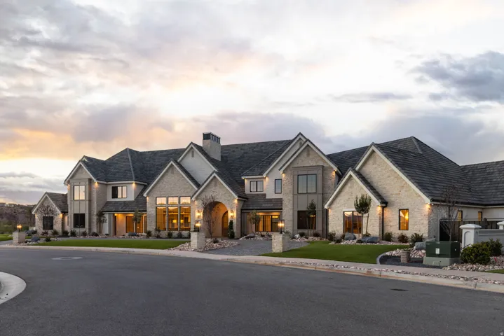 Stone and stucco exterior featuring multiple gables, an arched entryway, and a dark shingle roof