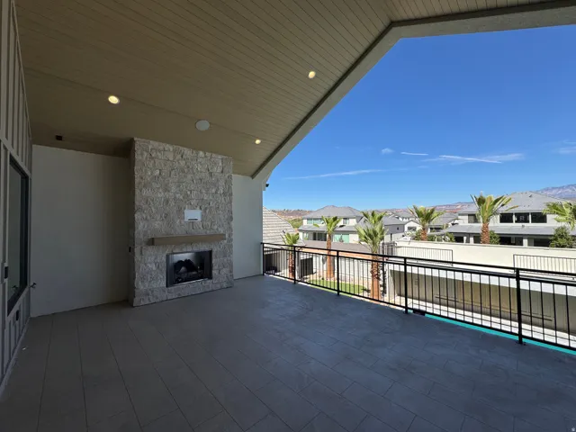 Expansive covered patio featuring a stone-clad fireplace with a wood mantel, recessed lighting, and tile flooring