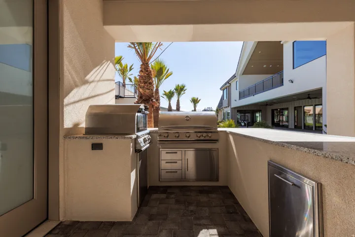 Outdoor kitchen featuring a built-in stainless steel grill, stone countertop, integrated stainless steel cabinetry, and paved flooring