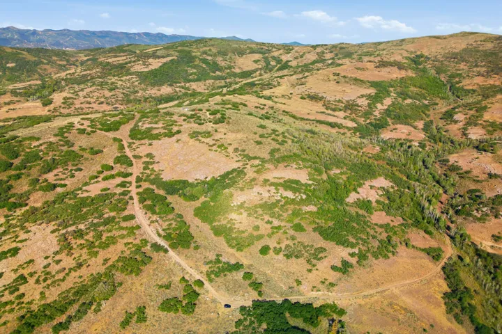 Expansive undeveloped land featuring rolling hills, varied natural vegetation, and distant mountain topography