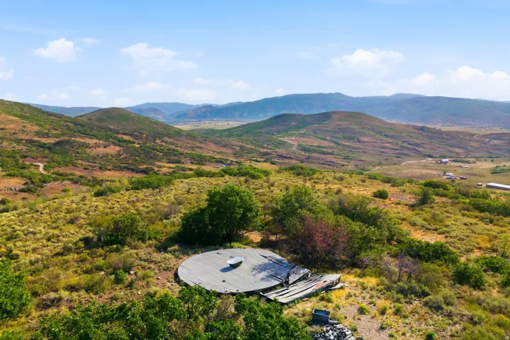 Expansive natural landscape with rolling hills, distant mountains, and scattered trees