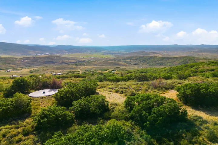 Expansive property featuring varied terrain, a concrete platform, and abundant mature trees