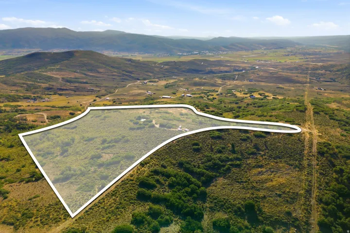 Expansive parcel with lush vegetation, a defined property boundary, and distant mountain scenery