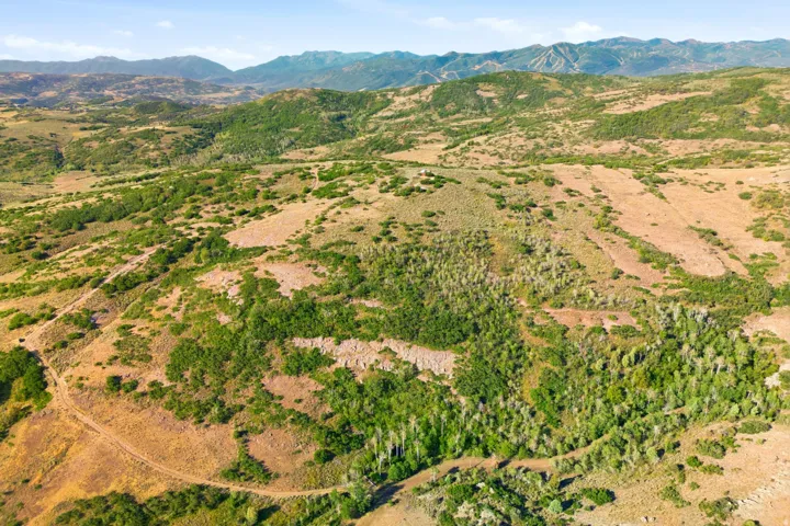 Expansive mountain terrain featuring varied elevations, natural vegetation, and distant mountain ranges