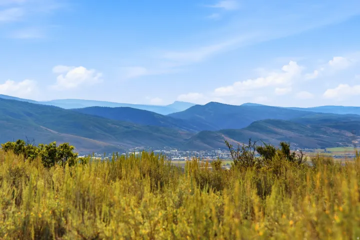 Expansive mountain range backdrop with distant structural elements under a clear sky