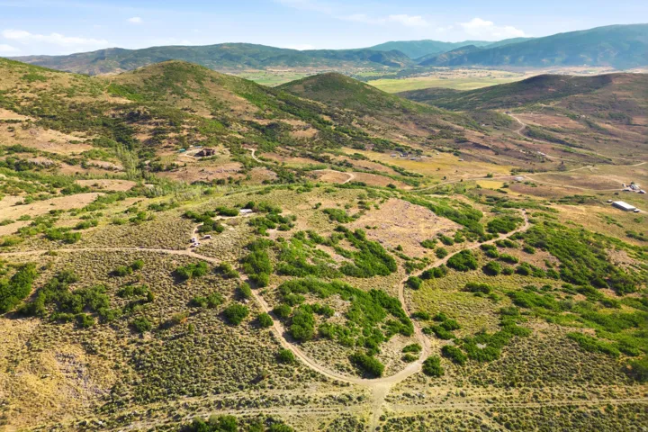 Expansive mountainous terrain with multiple winding paths and scattered green foliage