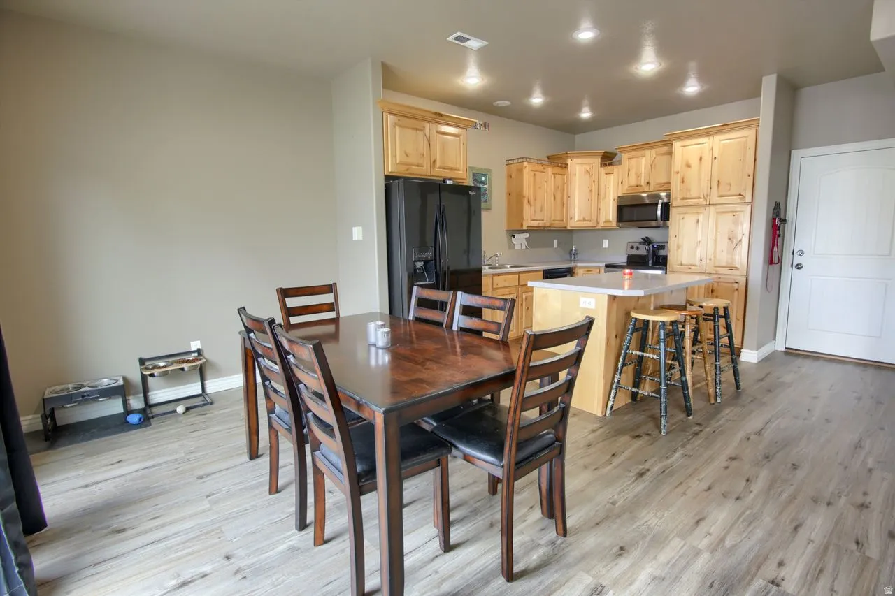 Wood-finish flooring throughout, kitchen with light wood cabinetry, white countertops, and stainless steel appliances