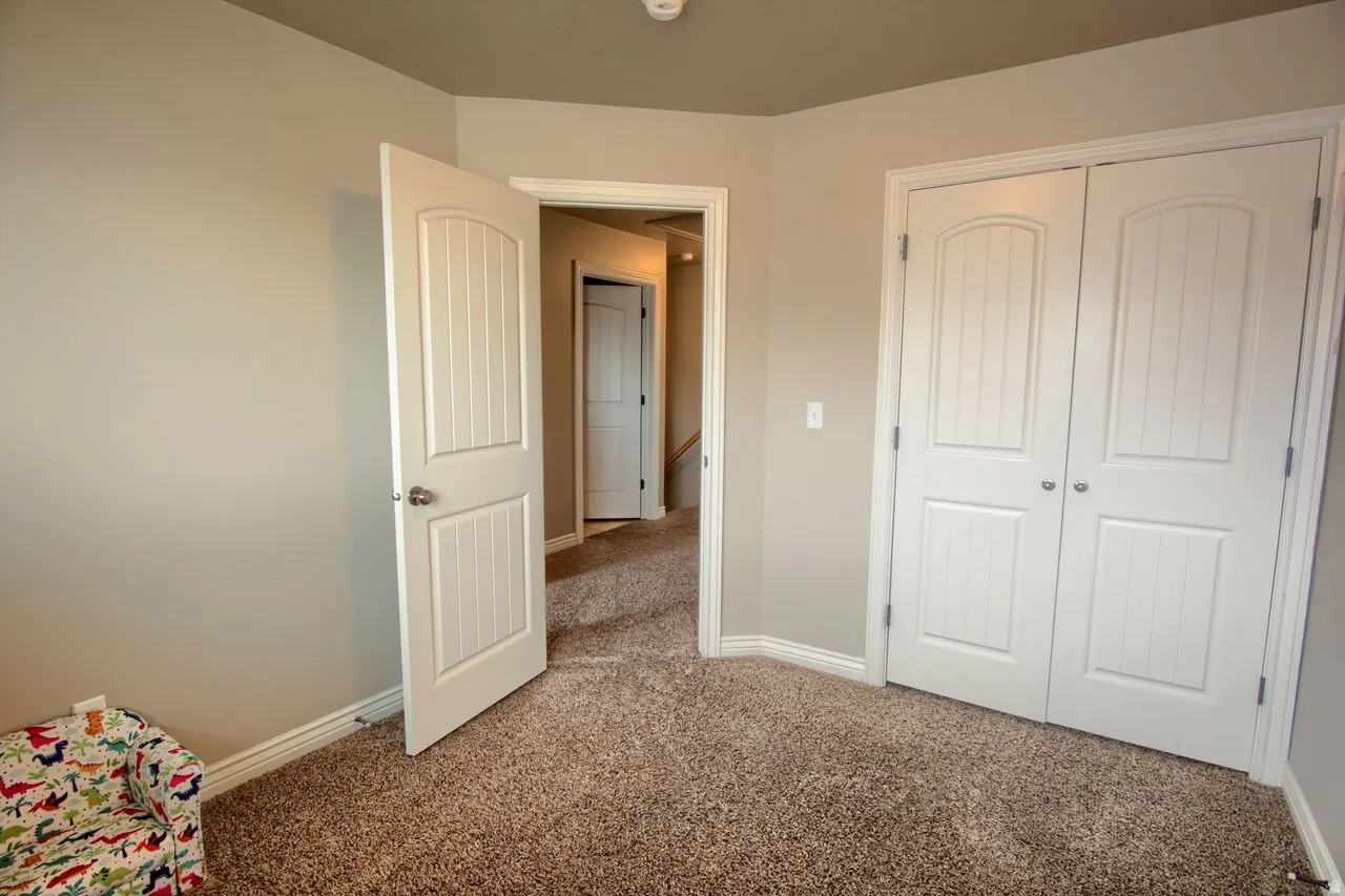 Neutral tone wall paint, carpeted flooring, white interior doors with paneled detailing, white trim